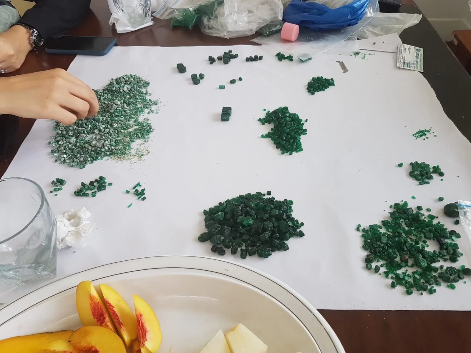 Lots d'émeraudes brutes triés par qualité sur une feuille de papier
